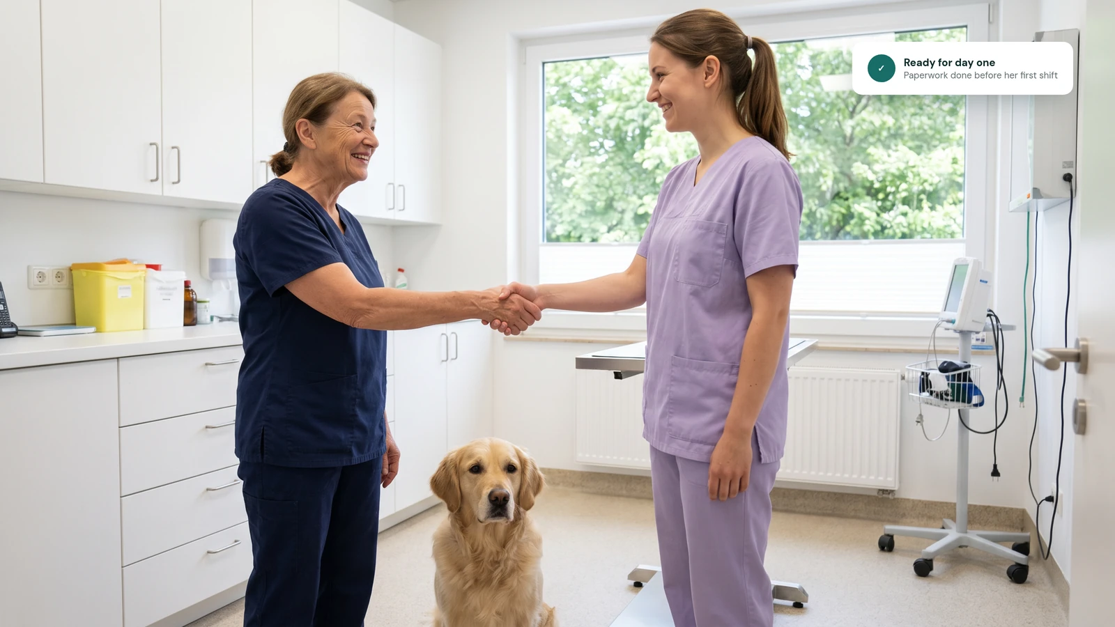 An experienced veterinary nurse welcomes a new assistant with a handshake on her first day while the clinic dog looks on.