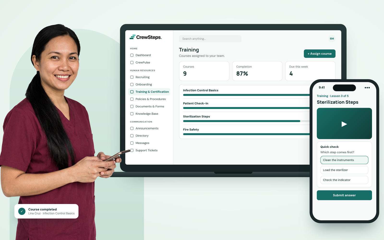 A smiling dental hygienist in wine-red scrubs holding her phone beside a CrewSteps laptop showing course completion and a phone with a training lesson and quick check.